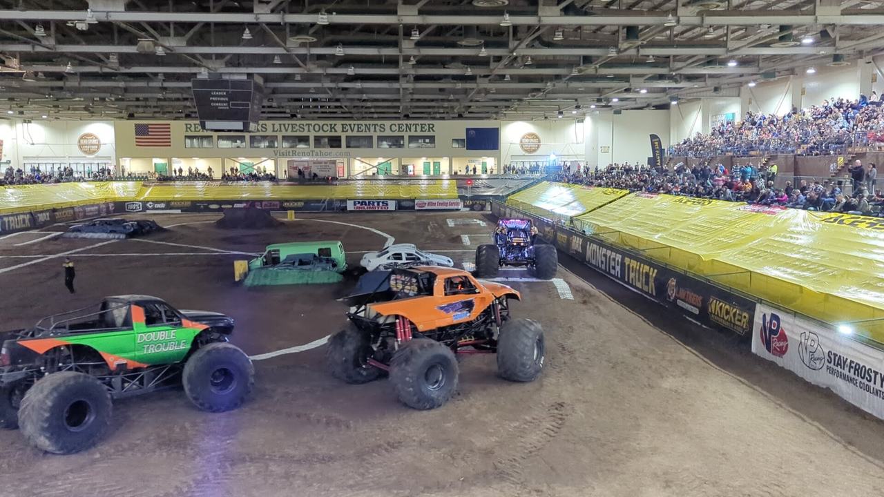Monster trucks on the dirt track in front of packed stands at the Reno Livestock Events Center