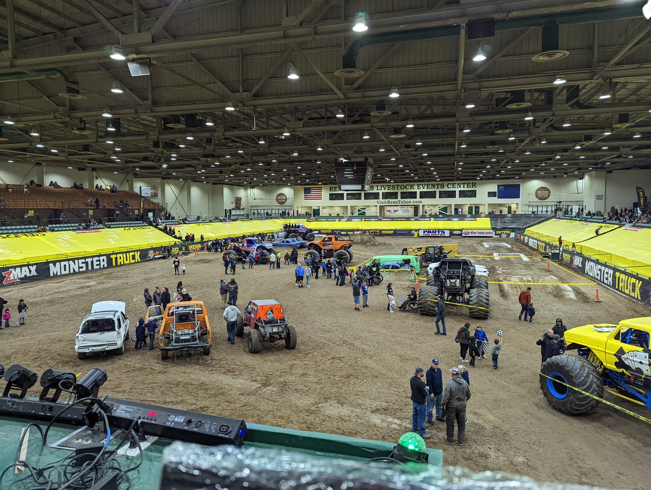 Families walking among the monster trucks on the track during the pit party, seen from my booth