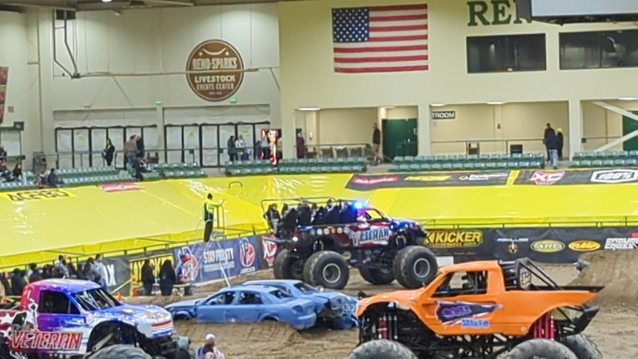 Monster trucks lined up under the American flag and the Reno Livestock Events Center sign