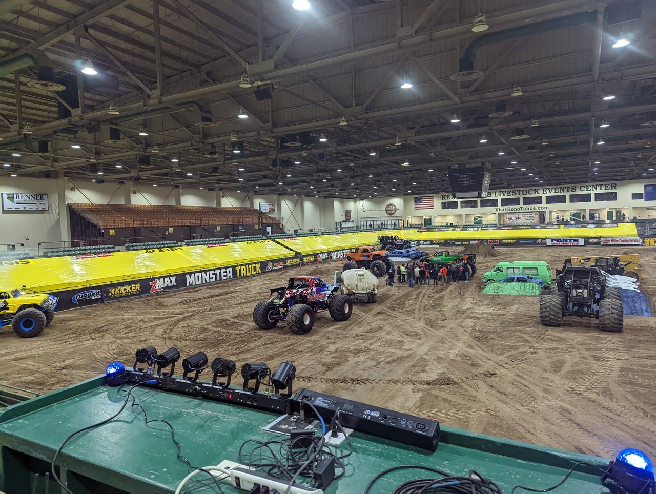 Monster trucks parked on the dirt, seen from the DJ rail