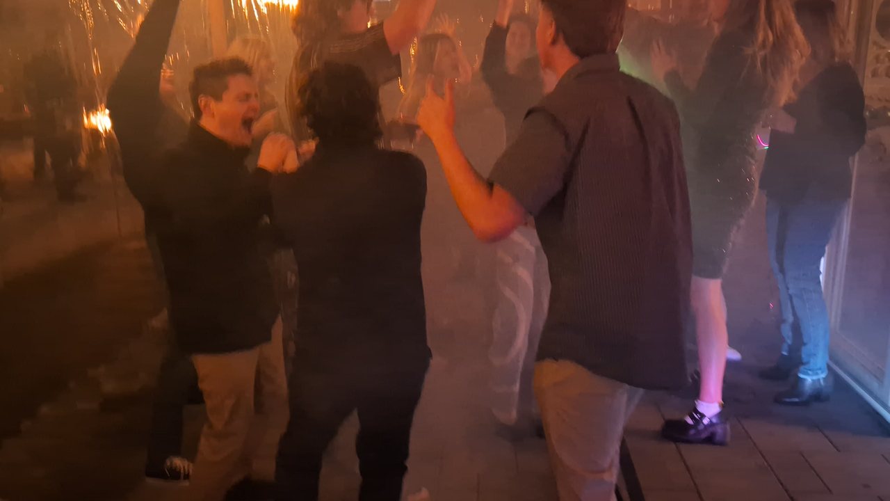 Guests singing and dancing with their hands up in the fog on the patio dance floor