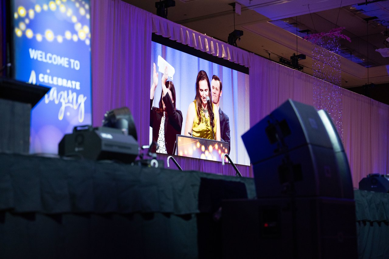 The big screen showing an honoree holding up her award