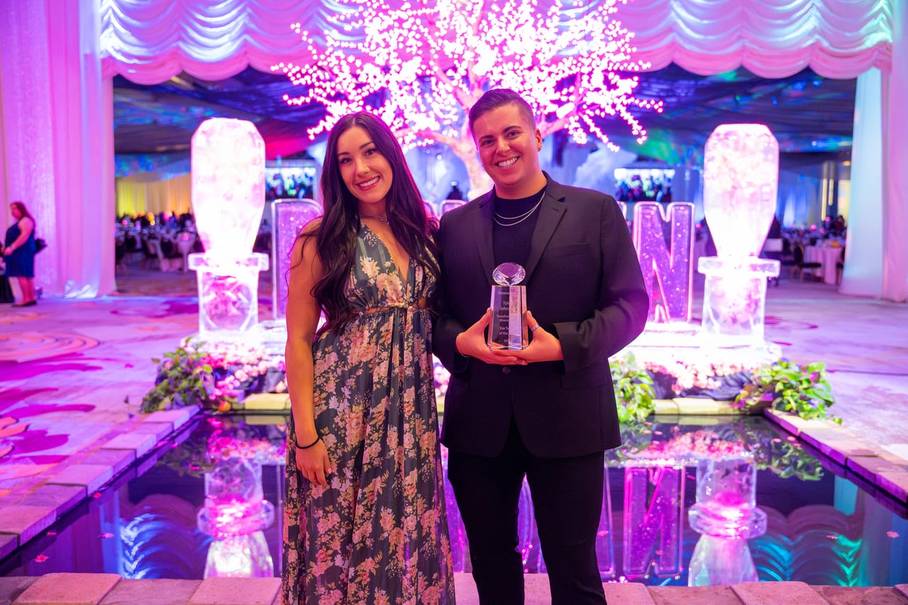 A Renown award winner holding his trophy with a friend at the ice sculpture