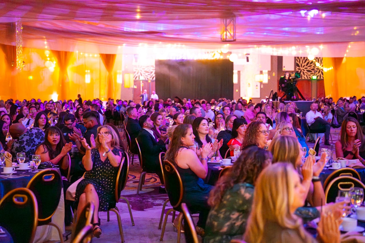 Renown guests applauding across the ballroom under lanterns and string lights
