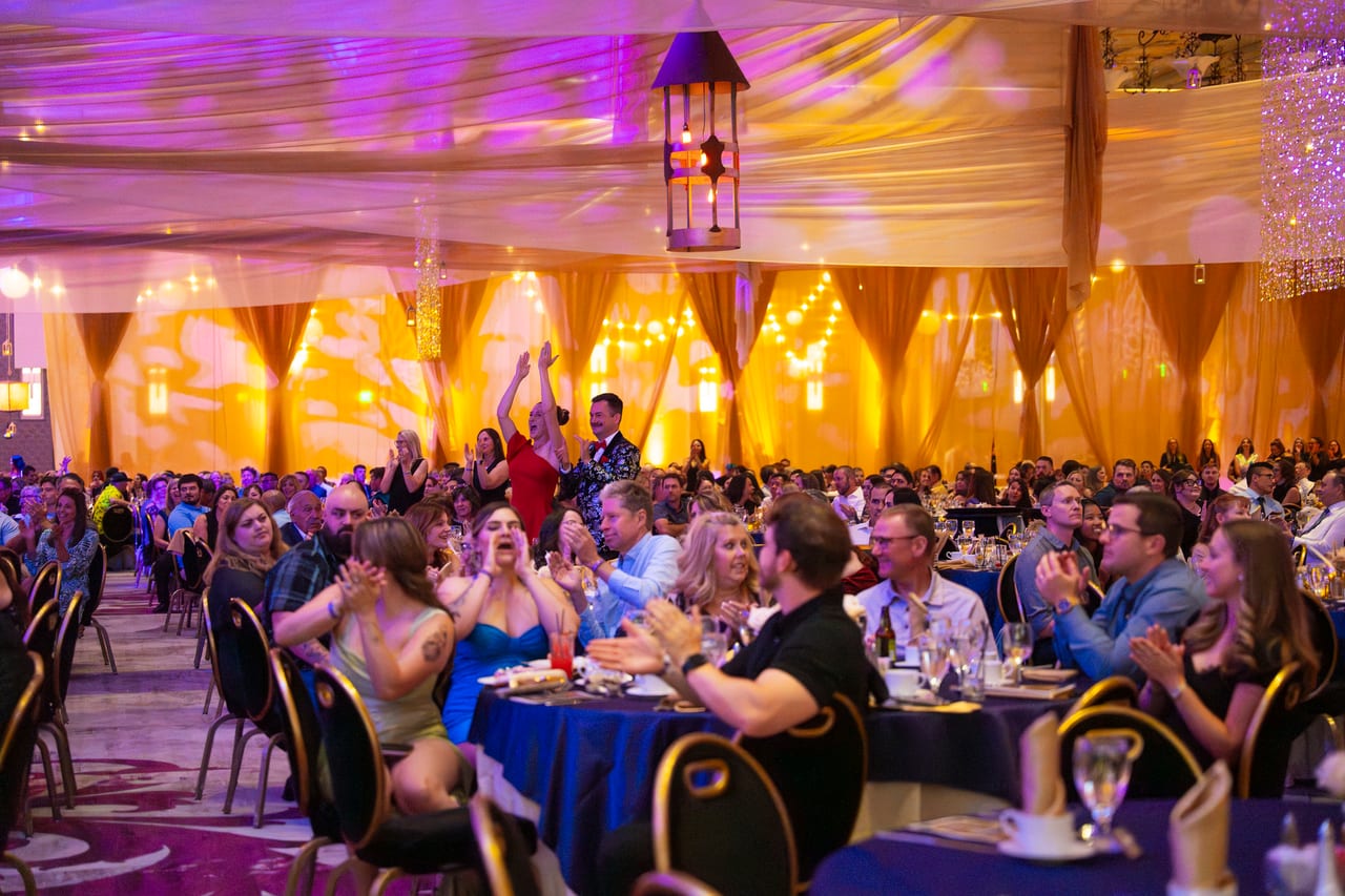 Renown guests cheering and waving their arms at their tables