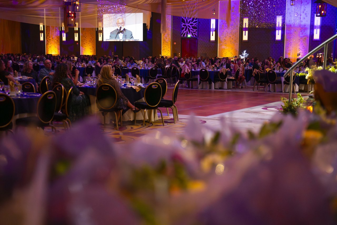 The ballroom seen past the bouquets during a speech