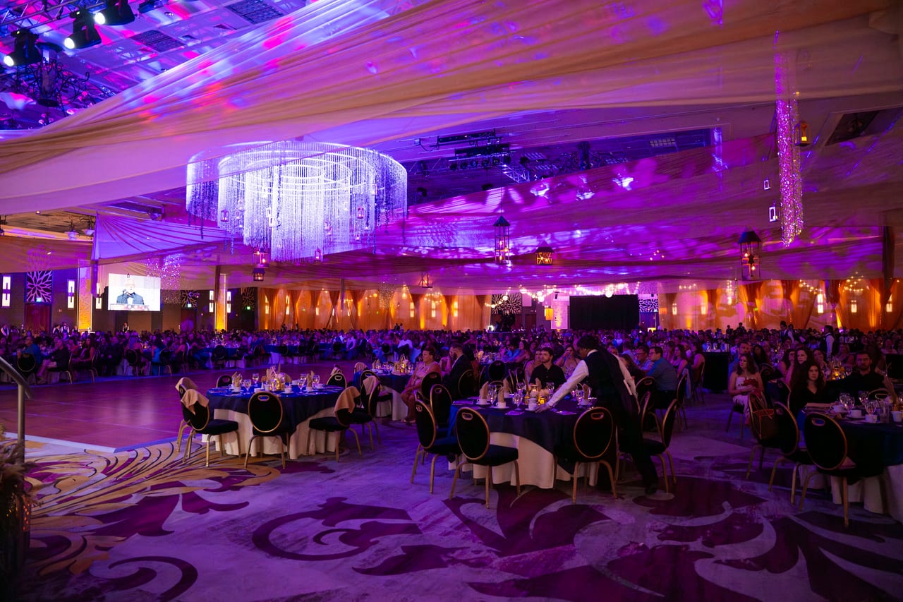The Tuscany Ballroom set for dinner under a crystal chandelier and purple light