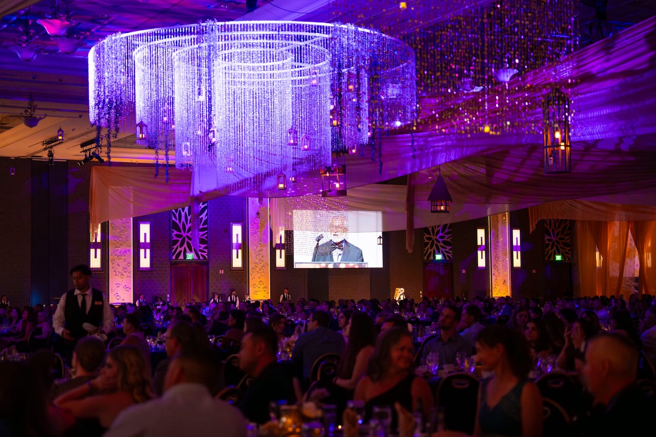 The packed Tuscany Ballroom under crystal chandeliers in purple light