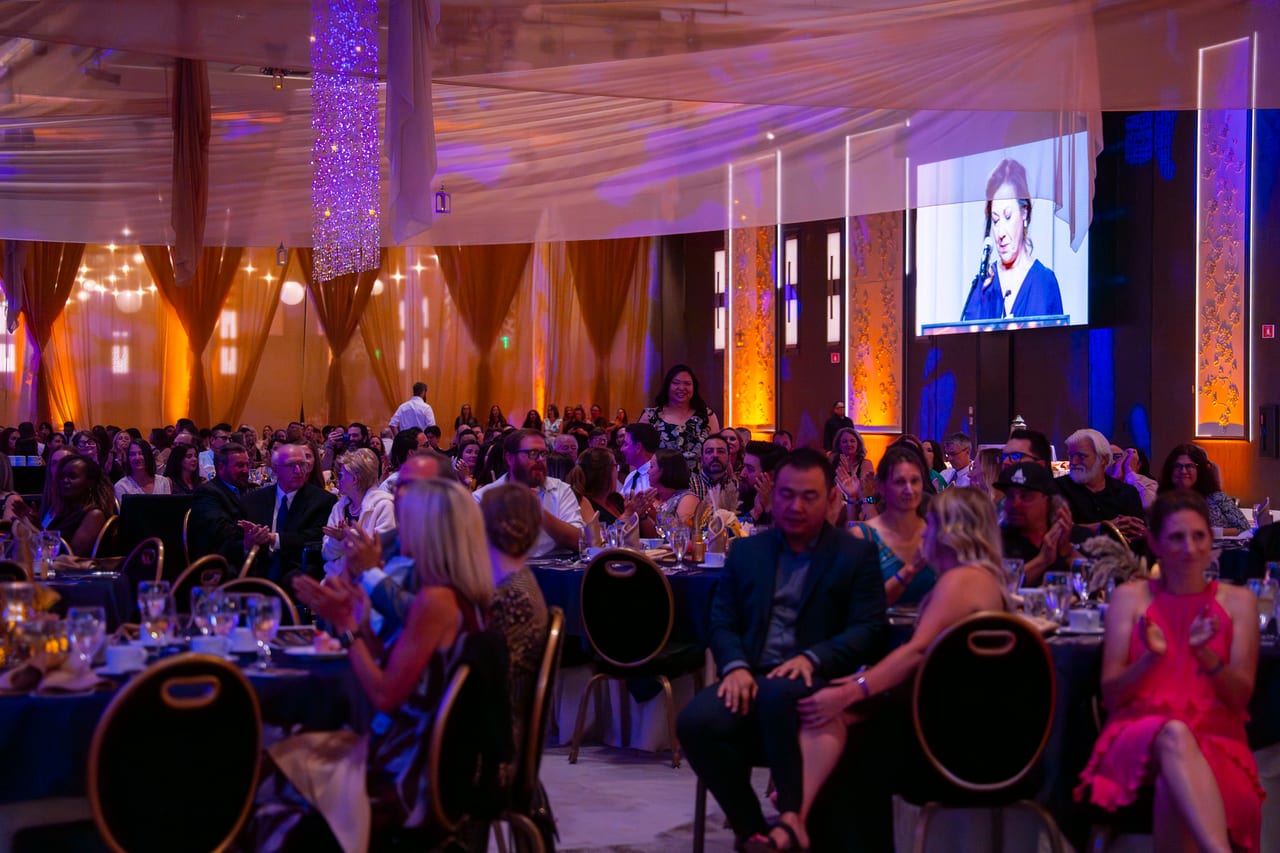 A full ballroom of Renown guests watching the program on the big screens