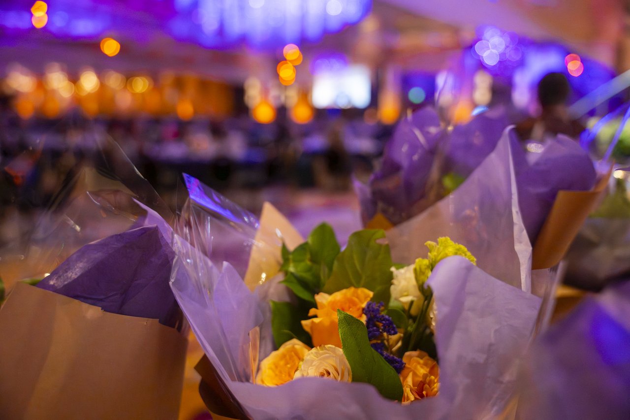 A close up of an honoree bouquet with the ballroom glowing behind it