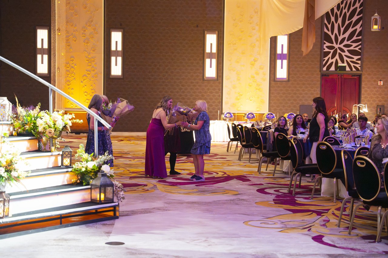 Renown honorees receiving bouquets beside the stage stairs