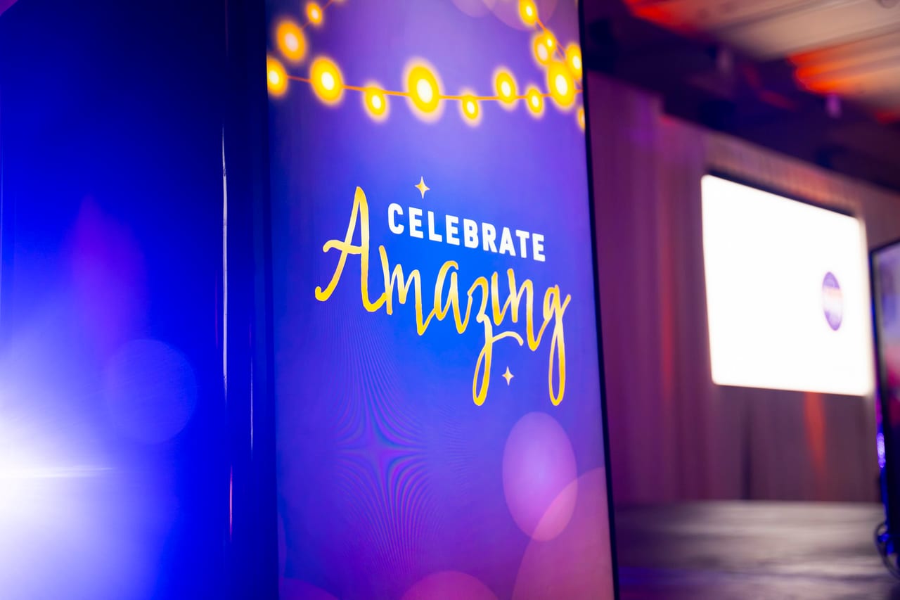 The Celebrate Amazing sign glowing under string lights at the ballroom entrance