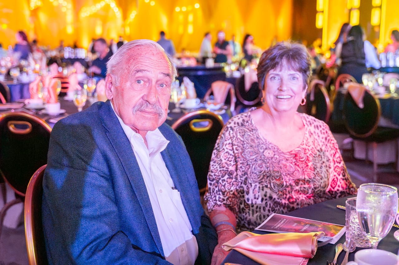 A Renown couple at their table in the gold lit ballroom