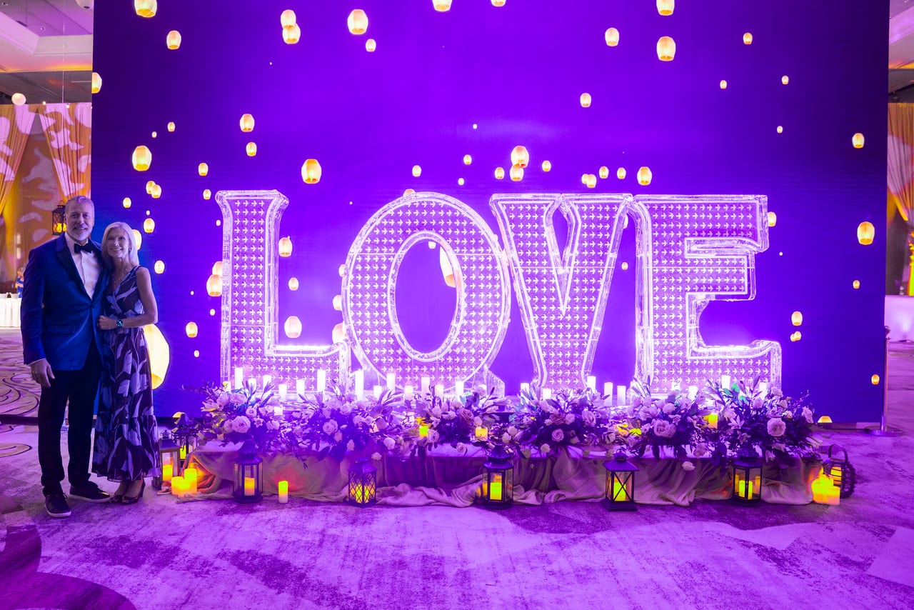 A Renown couple posing beside the giant LOVE letters and floating lanterns