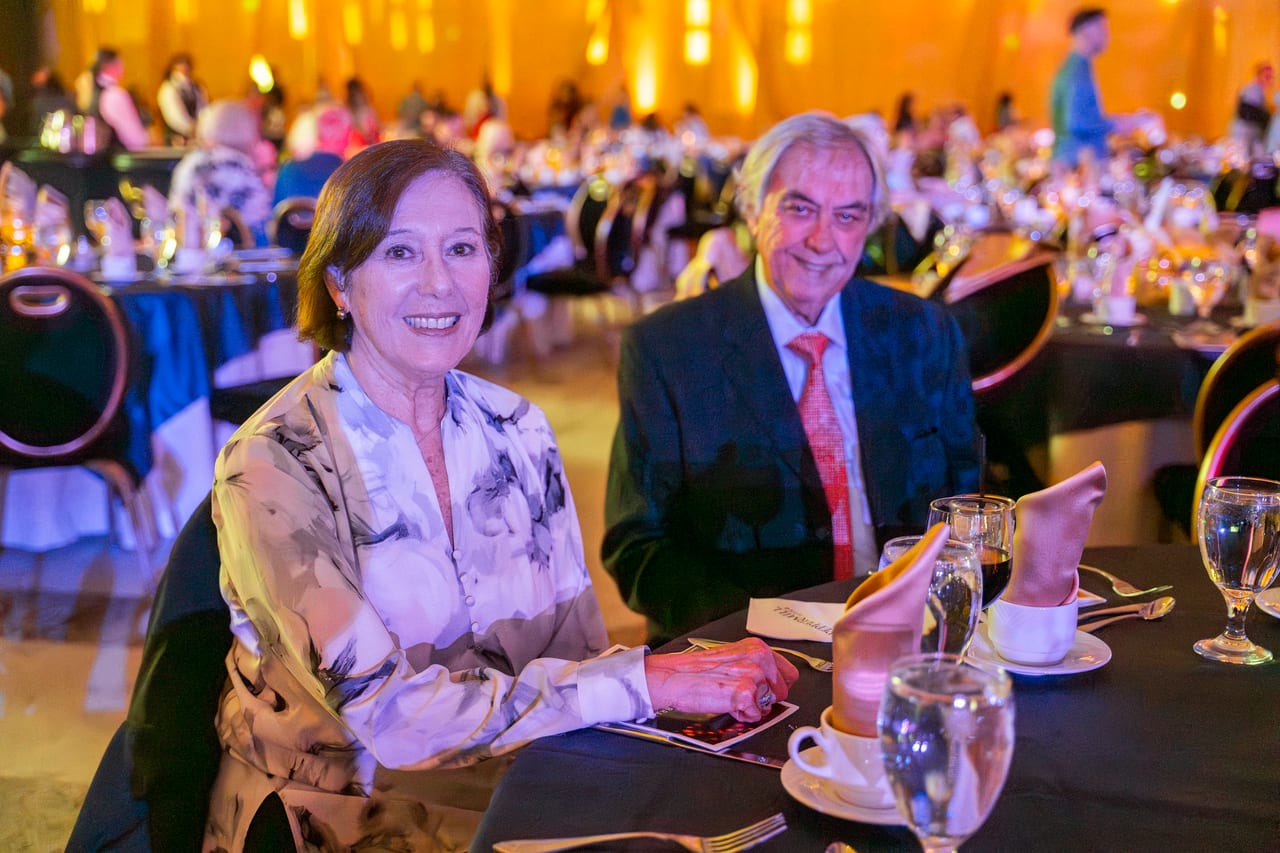 A Renown couple smiling at their table in the golden ballroom