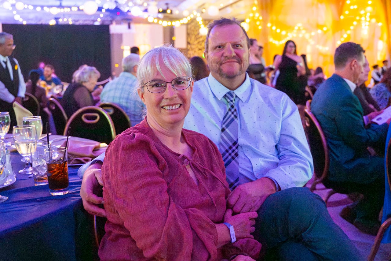 A Renown couple smiling at their dinner table in the ballroom