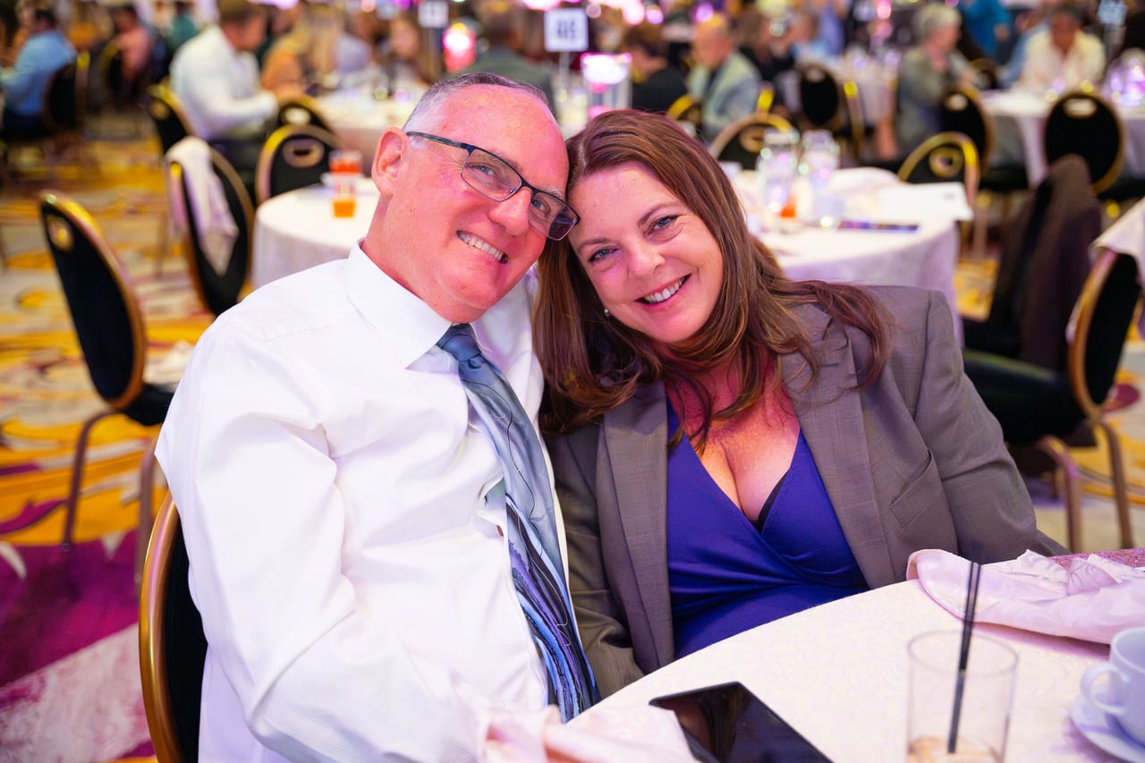 A Renown couple posing cheek to cheek at their table