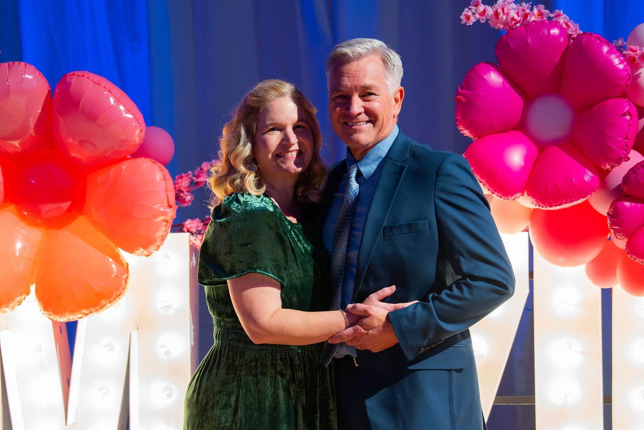A Renown couple holding hands in front of the balloon flowers