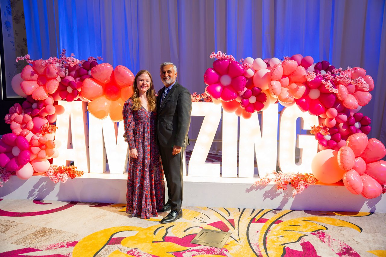 A Renown couple posing at the Amazing sign, her in a long patterned dress