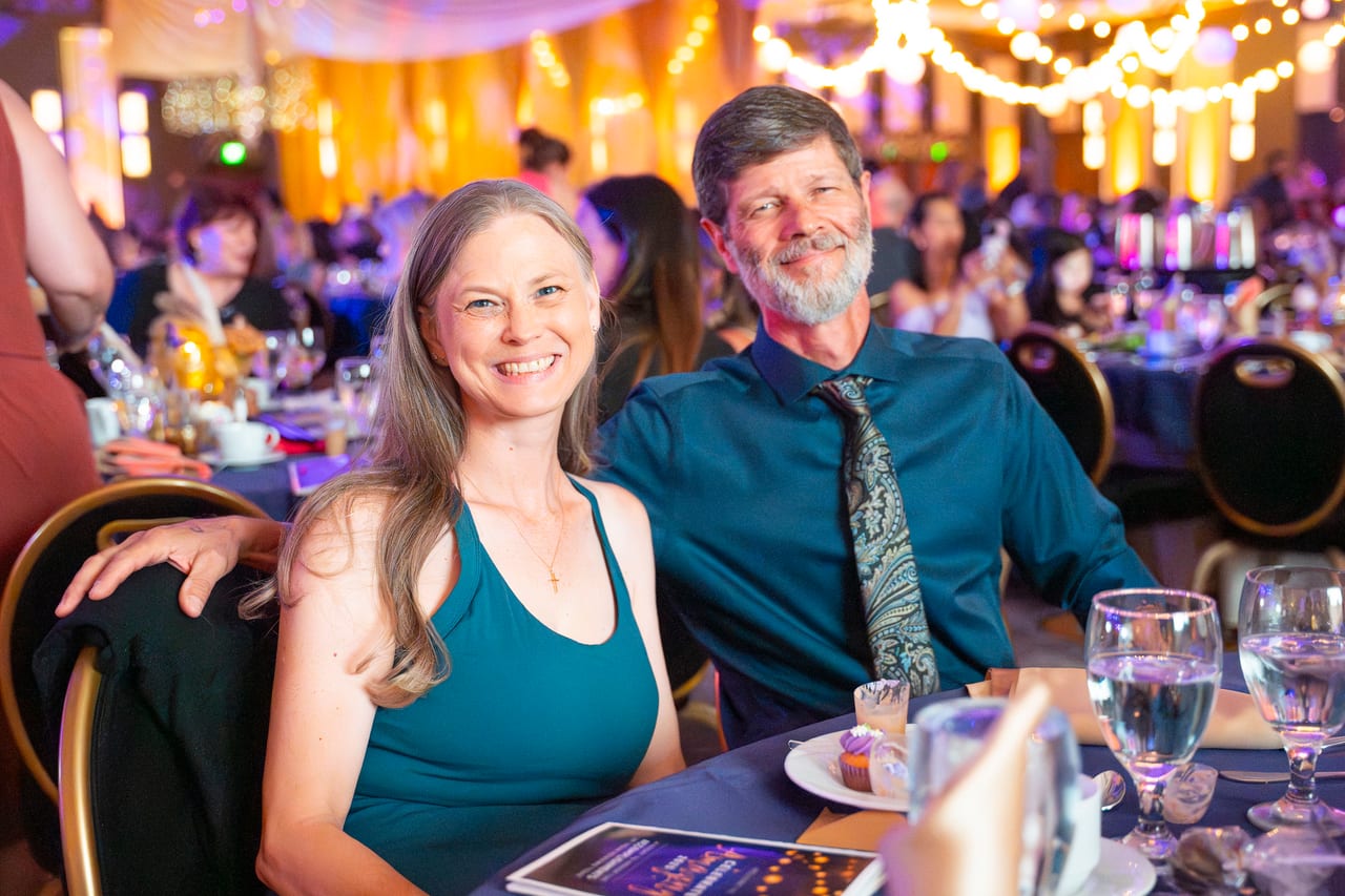 A Renown couple smiling at their table over dessert