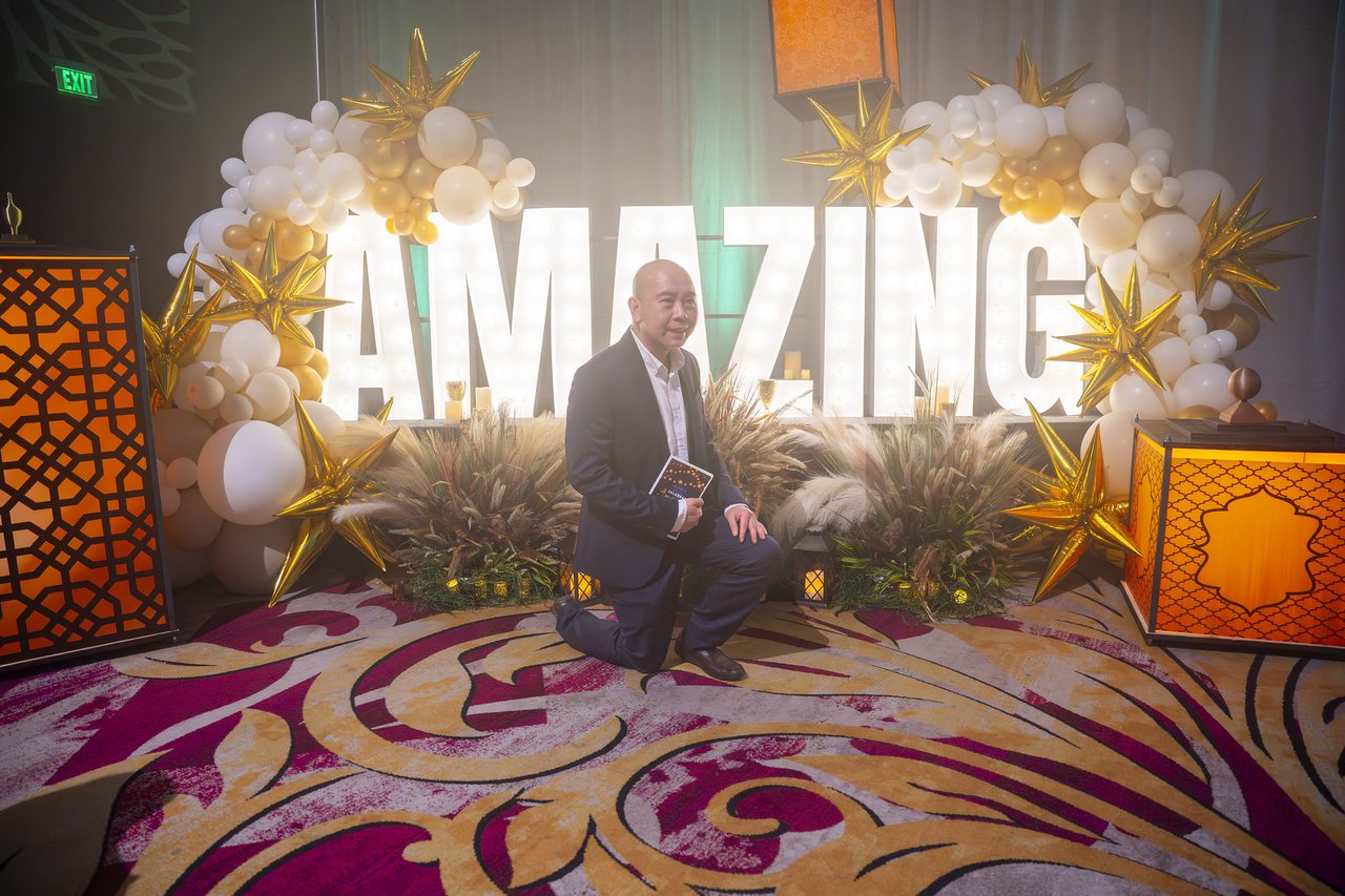 A Renown coworker kneeling in front of the Amazing letters