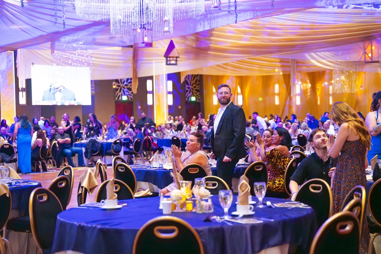 A Renown coworker standing at his table as the room applauds