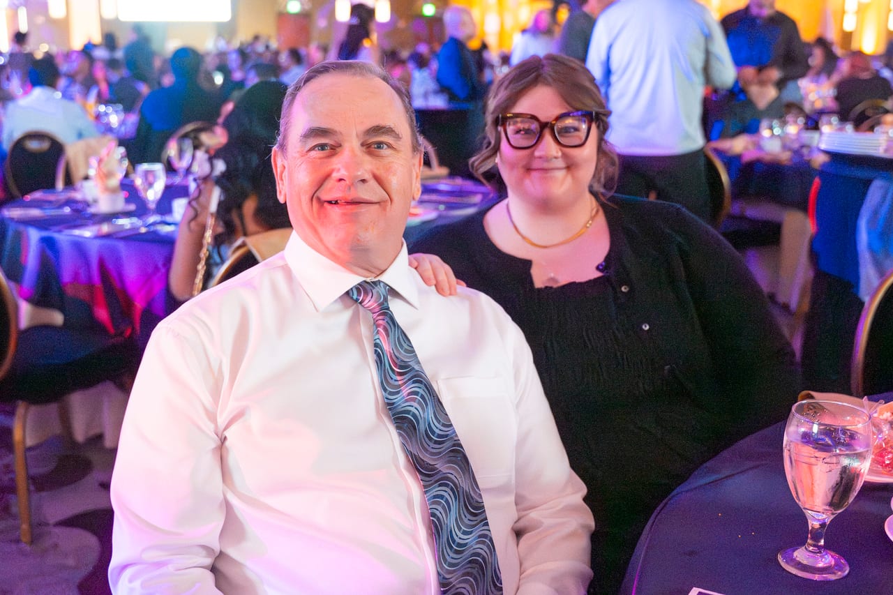 Two Renown coworkers smiling at their table in the busy ballroom