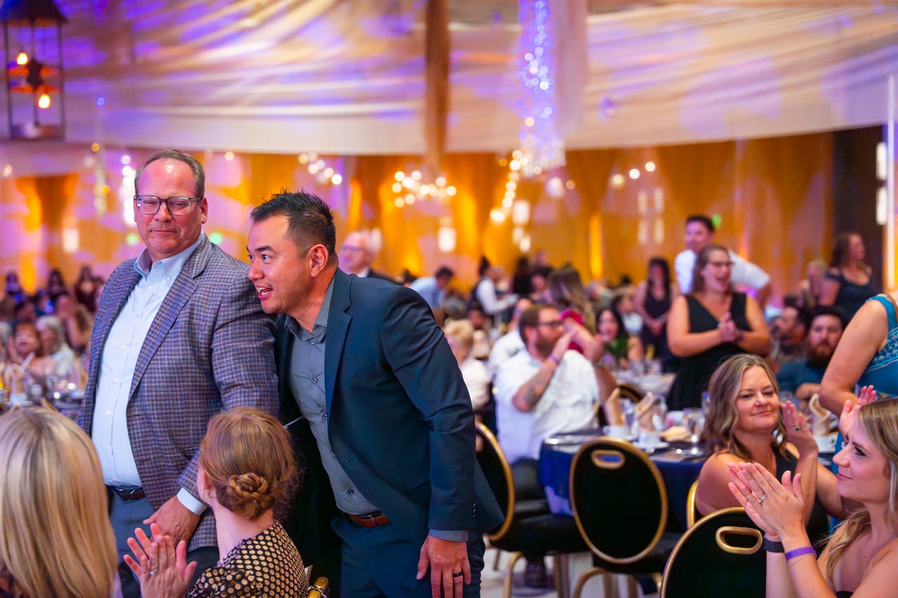 Renown coworkers cheering on a colleague walking up between the tables