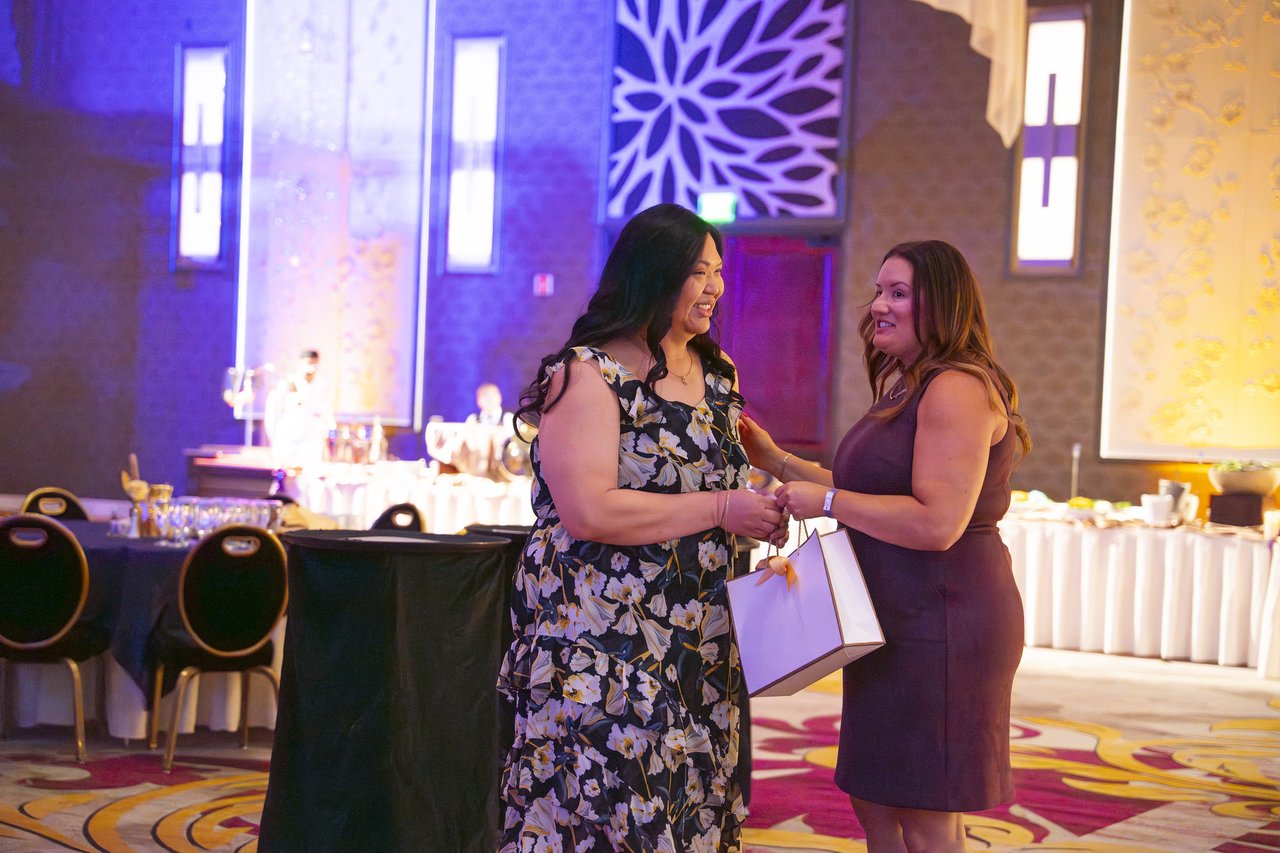 Two Renown coworkers sharing a gift bag by the tables