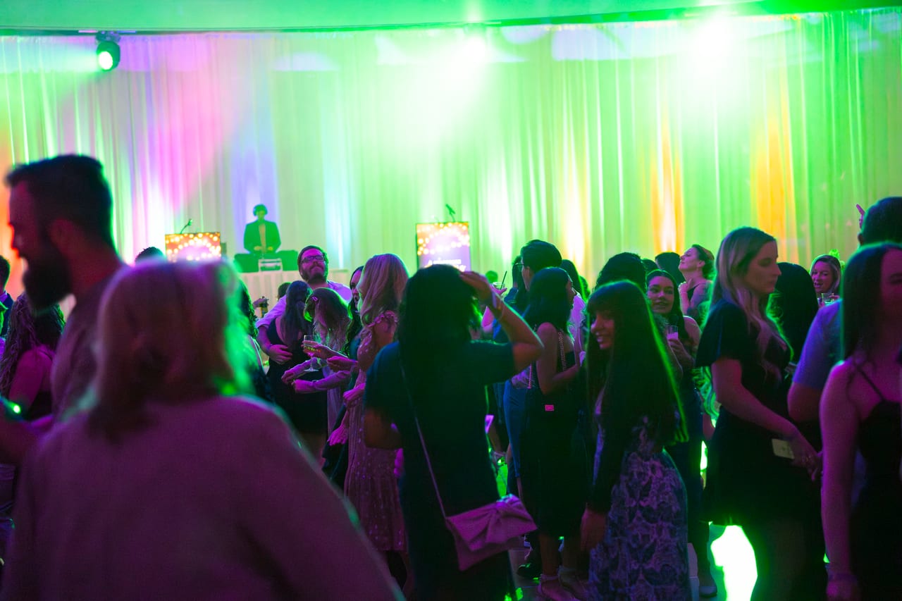 Renown guests on the dance floor under green and pink stage lights