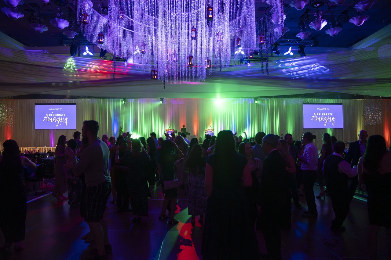 The packed dance floor under the crystal chandelier and colored lights