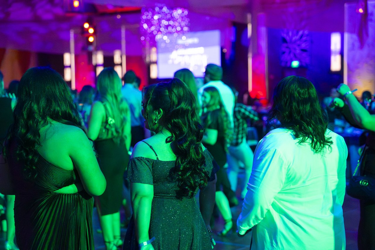 Renown guests dancing together under green and purple lights