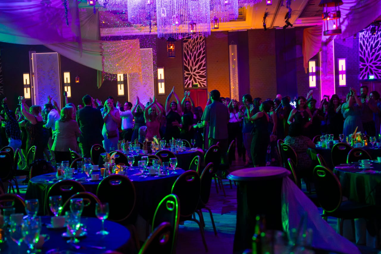 Renown guests dancing with their arms up between the tables