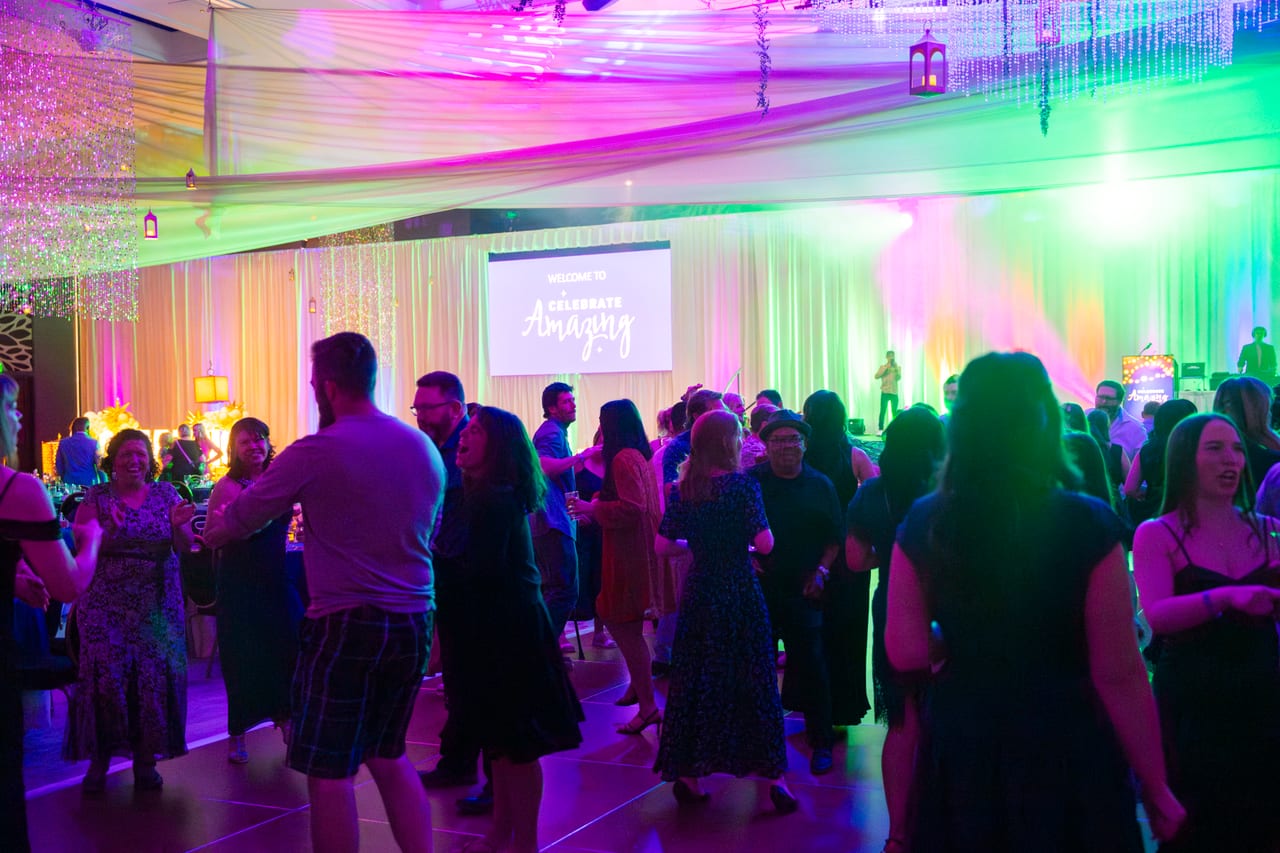 Renown guests dancing under purple and green lights below the welcome screen