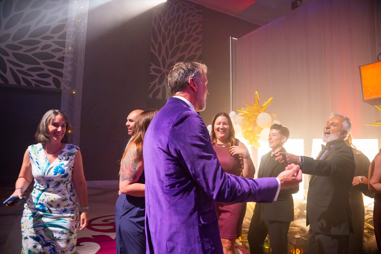 The emcee in a purple jacket dancing with Renown honorees on stage