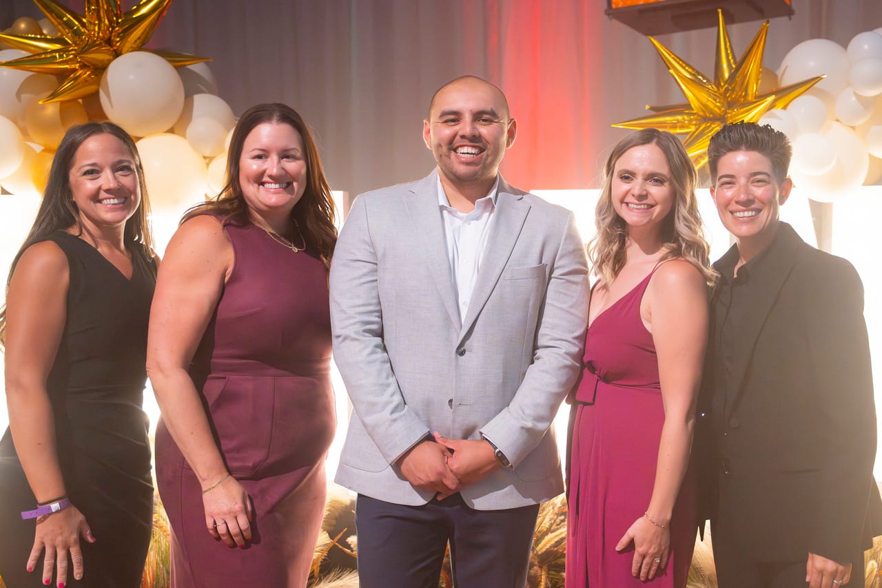 Five Renown coworkers smiling together at the gold star balloons
