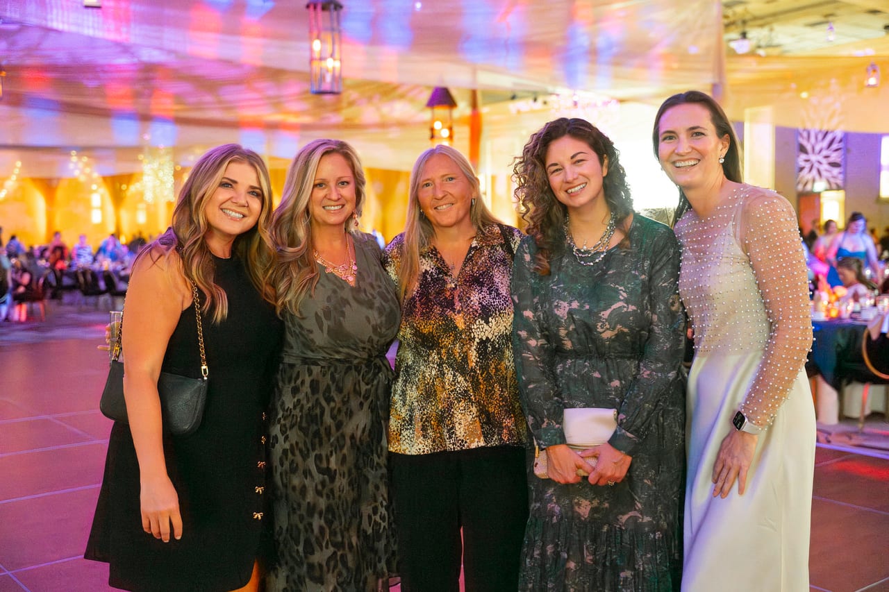 Five Renown coworkers posing together in the warm lit ballroom