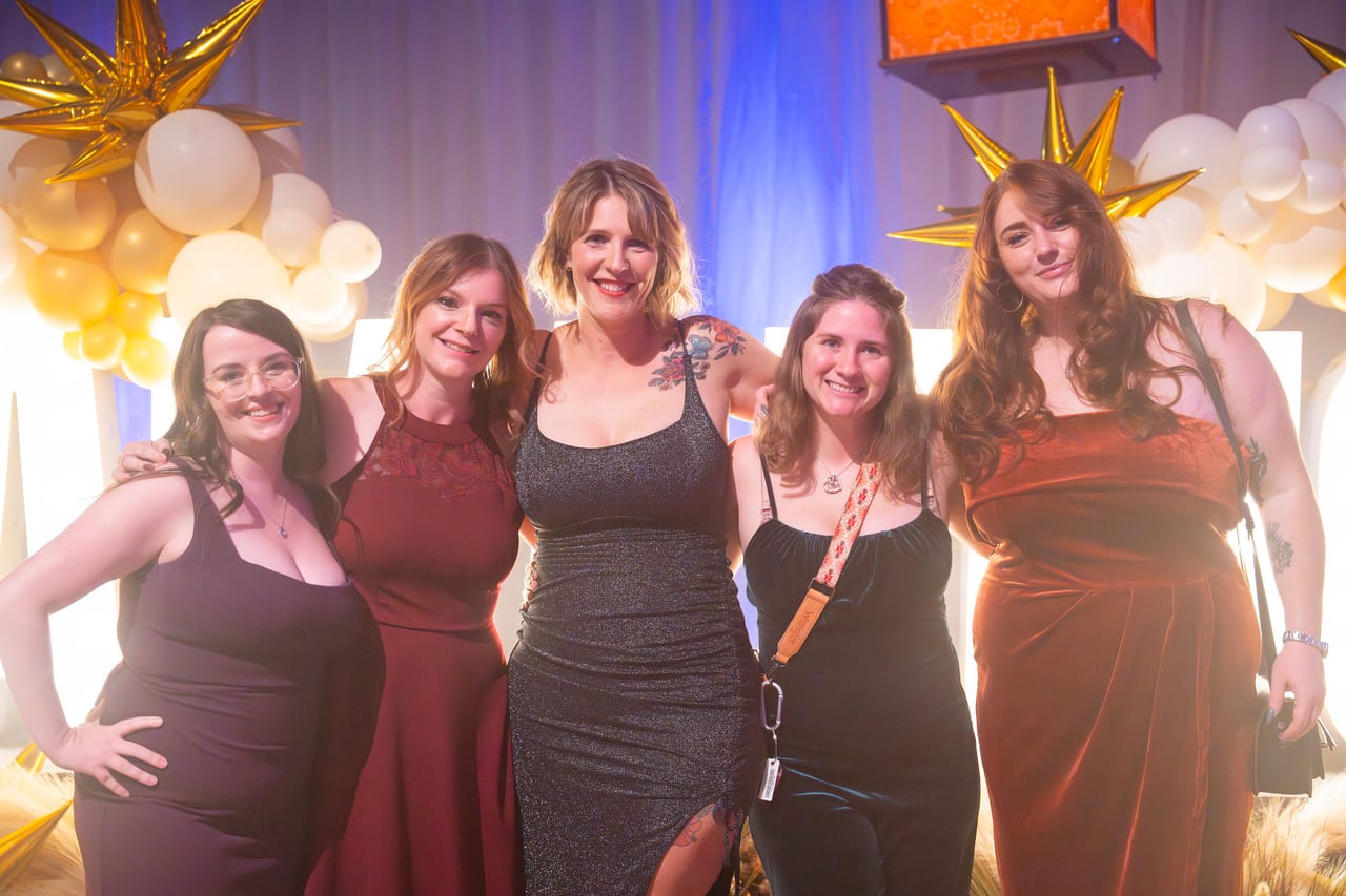Five Renown friends arm in arm at the gold and white balloon wall