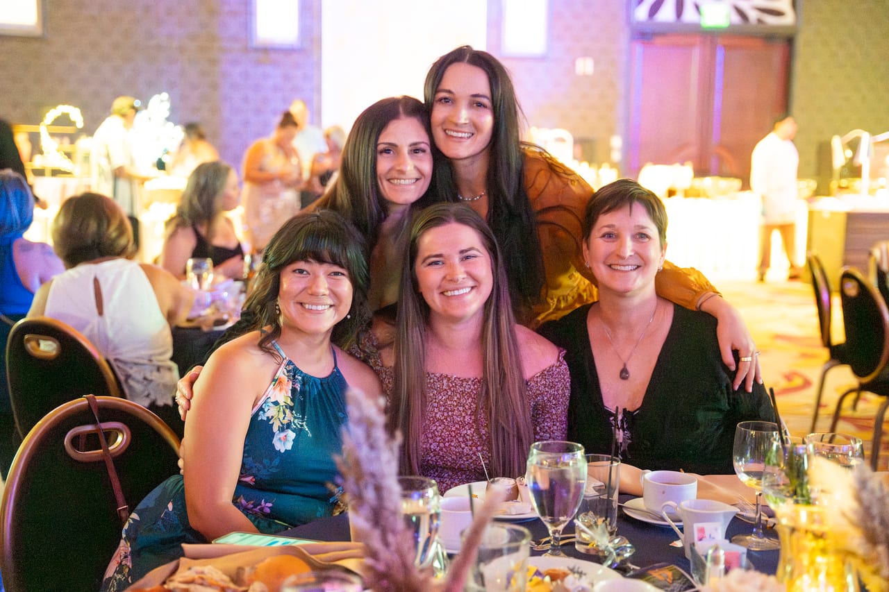 Five Renown friends squeezed together for a photo at their table