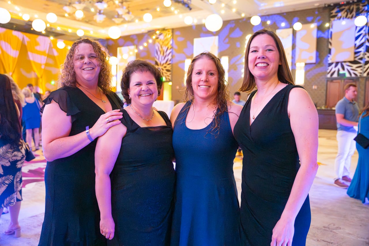 Four Renown friends arm in arm in the string lit ballroom