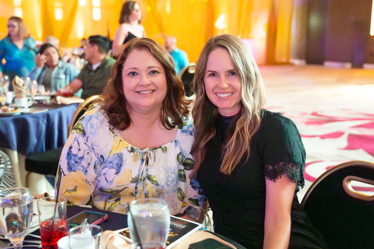 Two Renown friends smiling side by side at dinner