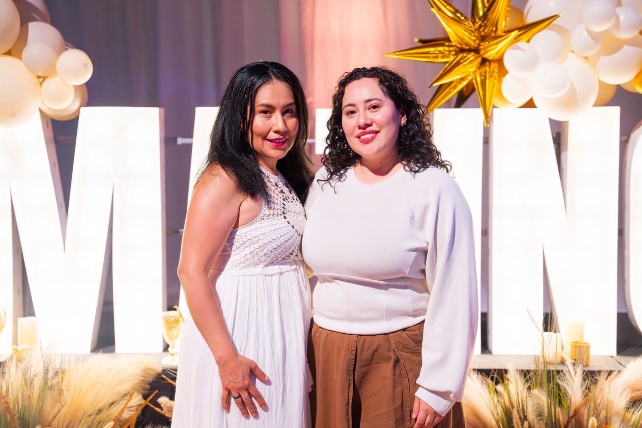 Two Renown friends in white posing at the glowing letters