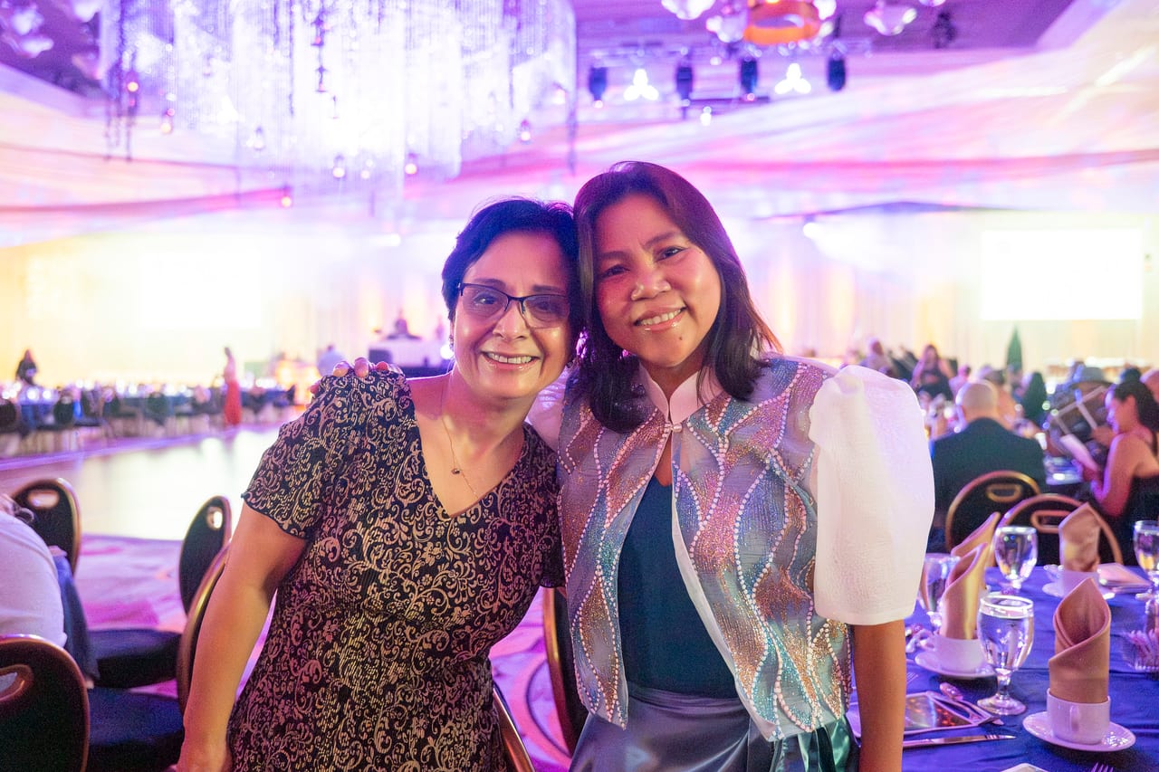 Two Renown friends posing by the dance floor under the chandeliers