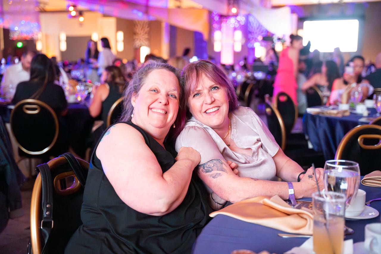 Two Renown friends hugging and smiling at their table