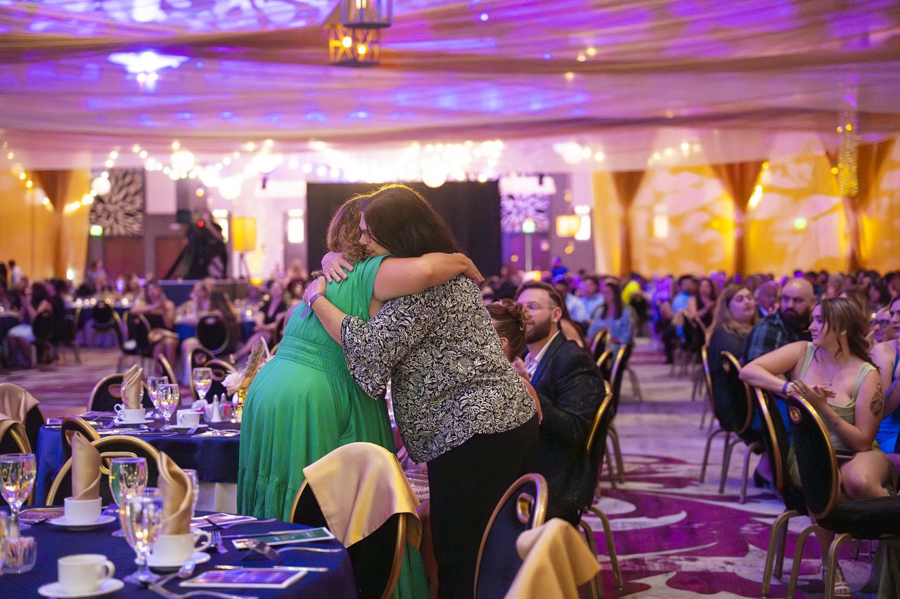 Two Renown friends hugging between the dinner tables