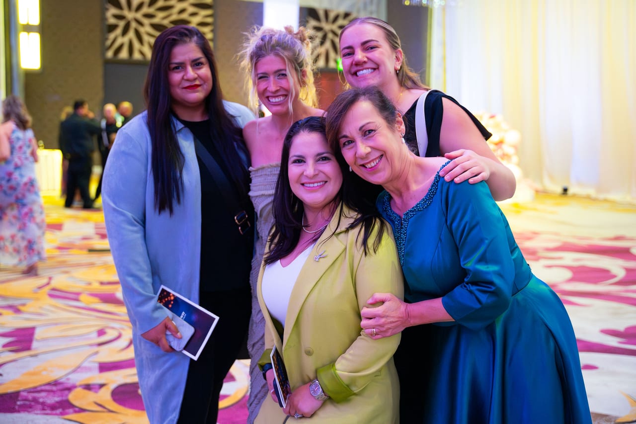 Five Renown friends hugging for a photo in the ballroom