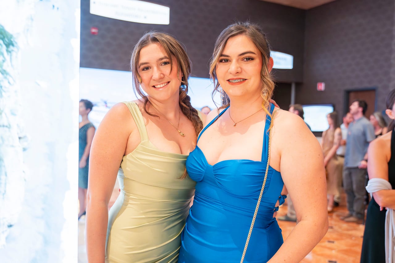 Two Renown friends in blue and gold dresses smiling at the entrance