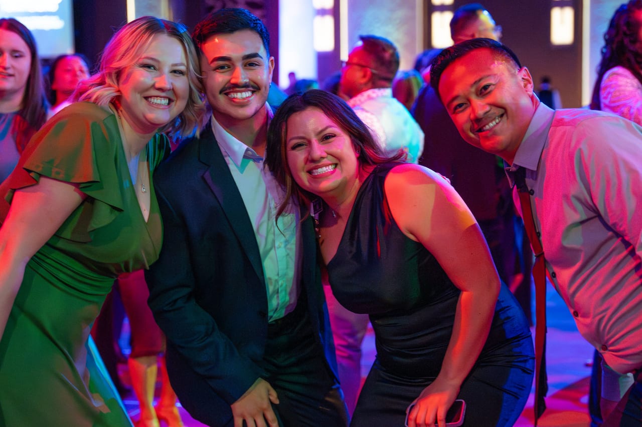 Four Renown friends leaning in for a photo on the dance floor
