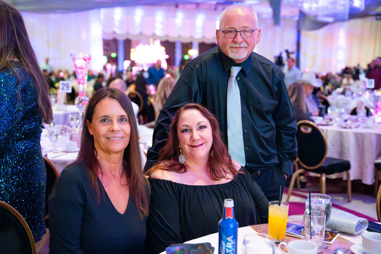 Two Renown friends and a coworker in a tie smiling at their table