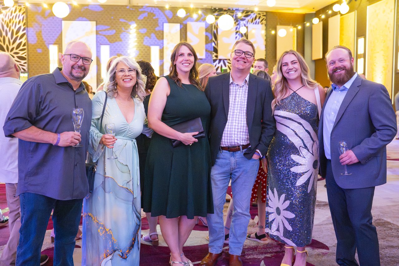 Six Renown friends smiling with their drinks in the ballroom